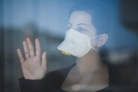 Photo of woman in mask behind glass by Önder Örtel on Unsplash